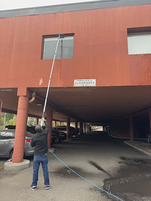 TBM technician using water-fed pole system for high-reach commercial window cleaning